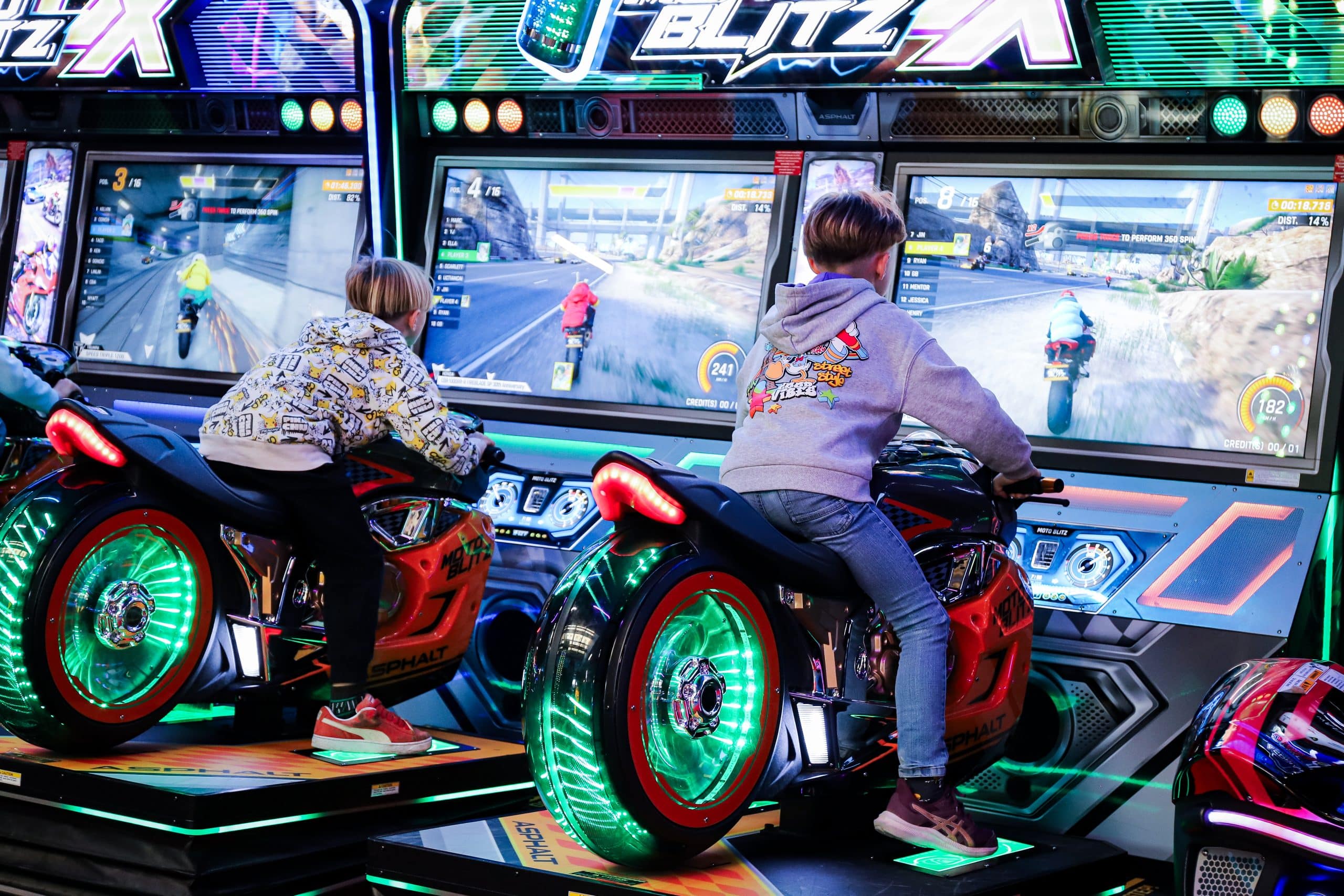 Enfants s’amusant sur des motos arcade dans une salle de jeux indoor