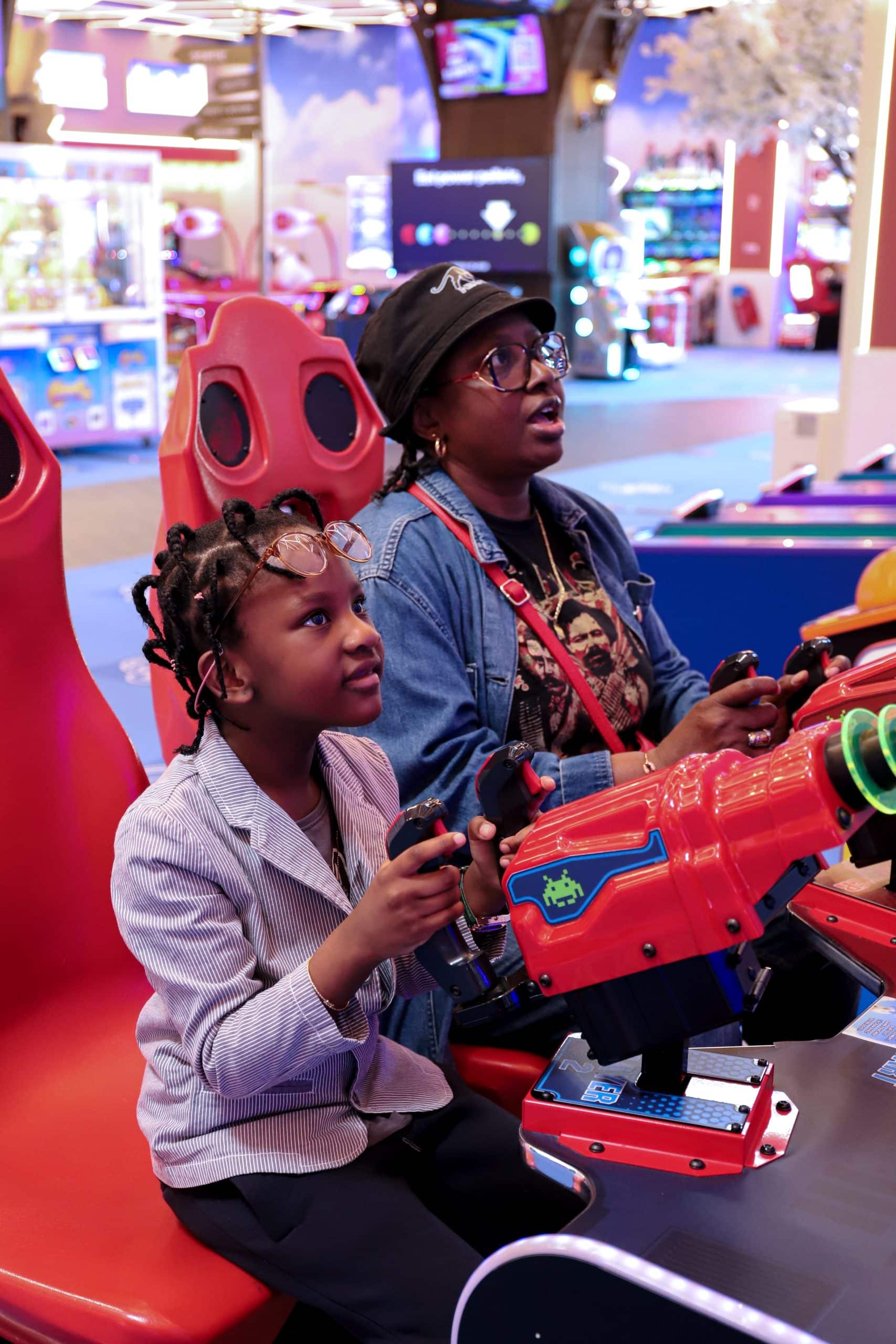 Maman jouant à un jeu de tir avec sa fille dans une salle d’arcade