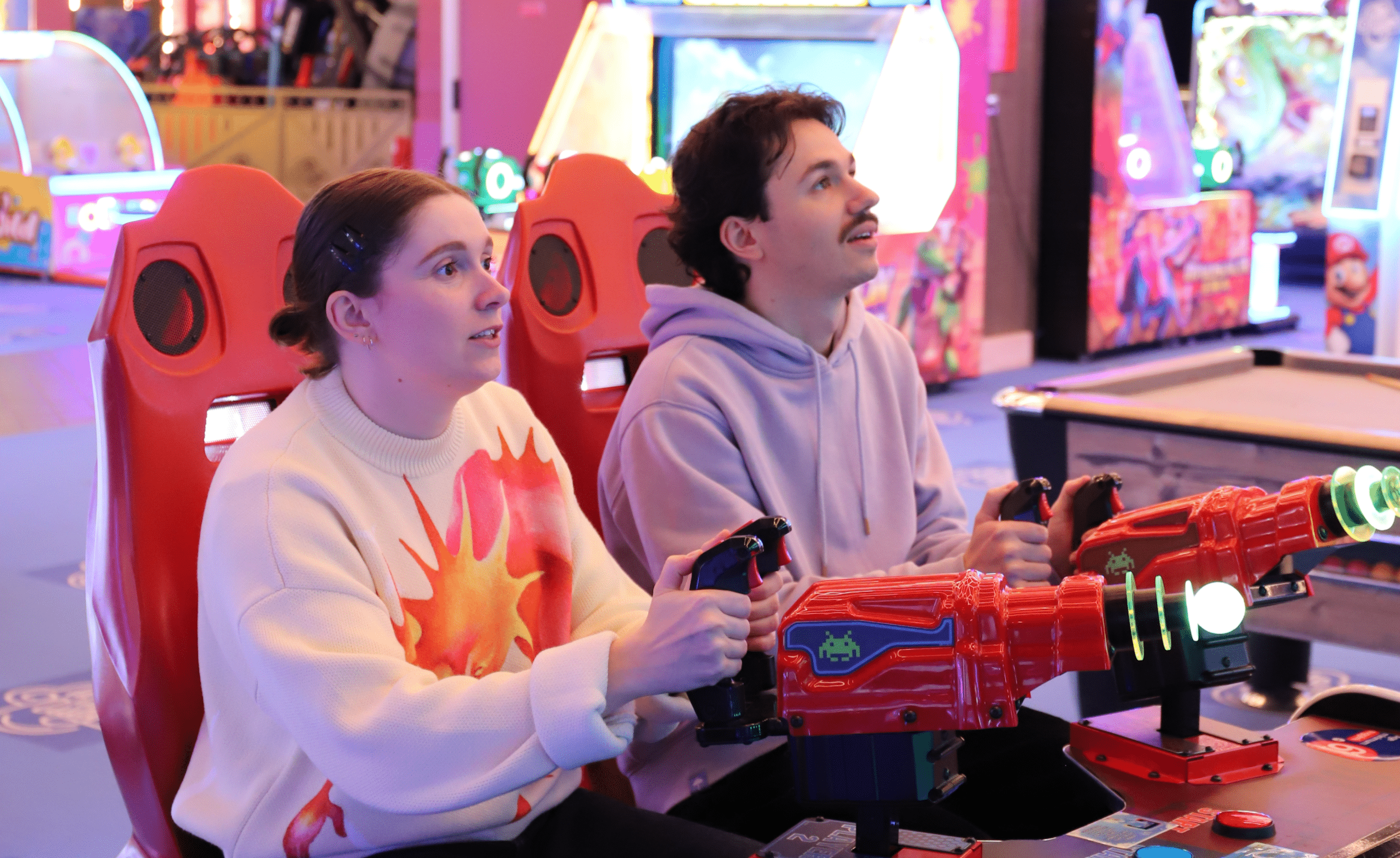 Un couple en train de jouer ensemble à une borne d'arcade de tir laser chez La Tête dans les Nuages.